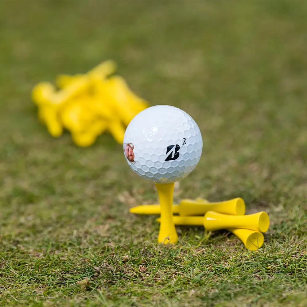 A bridgestone golf ball positioned on a PTS® Step Tees in grass turf.