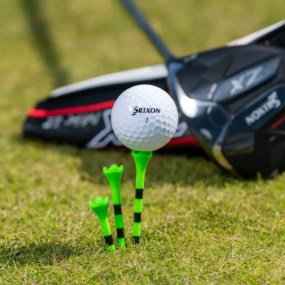 Three pride Performance citrus green striped tees positioned next to a Srixon golf ball.