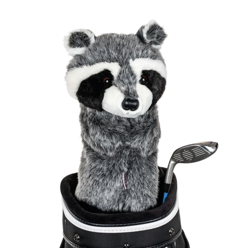 A raccoon-shaped golf club head cover sitting in a golf bag, with a club peeking out.