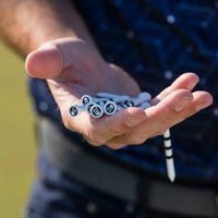 A person holding a couple of special edition skull and bones golf tees in their hand.