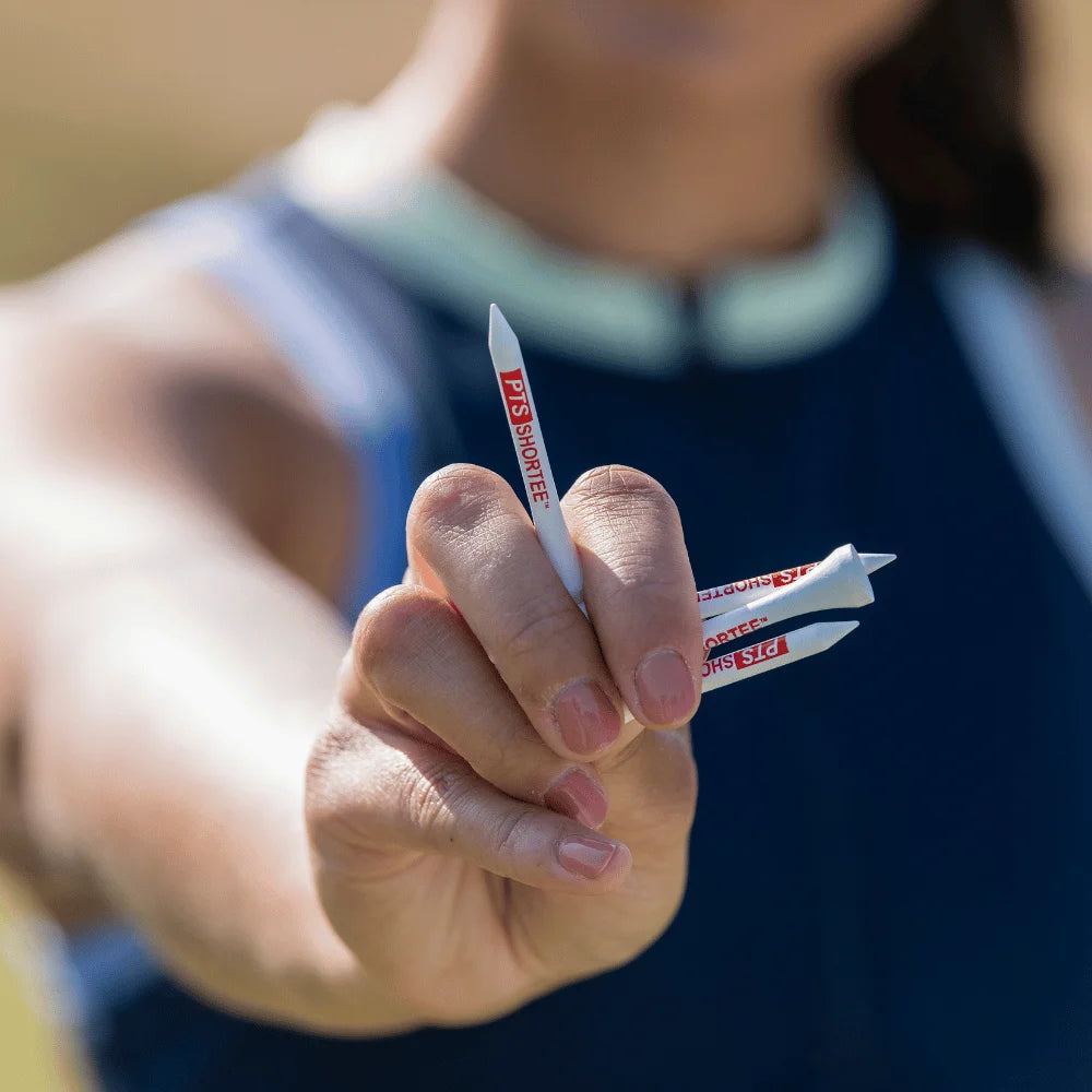 A woman holding four 2-1/8" professional tee system tees in her hand. 