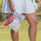 A woman carrying a large bag of white pride golf tees on a golf course. 