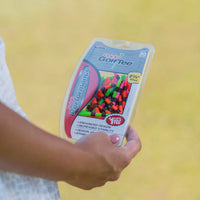 A person holding a citrus mix pride performance golf tee packaging. 