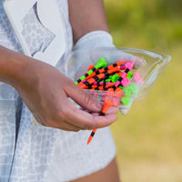 A person holding a citrus mix pride performance golf tee packaging. 