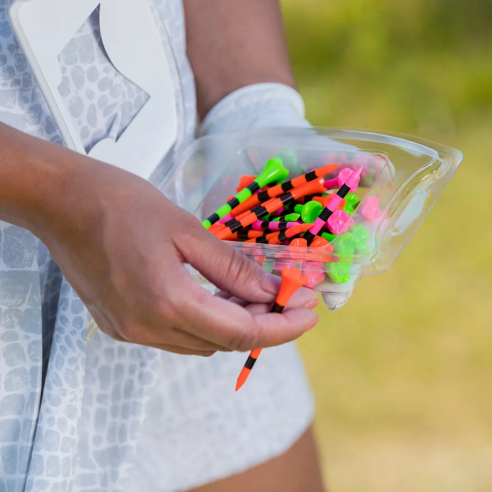 A person holding a citrus mix pride performance golf tee packaging. 