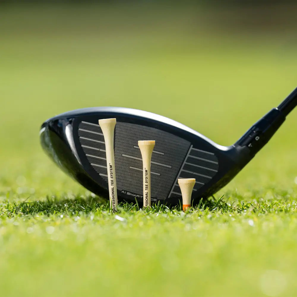 The three different PTS bamboo tee lengths in green turf with a golf club positioned behind them. 