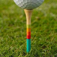 Close-up of a golf ball on a 3 1/4-inch bamboo tee, showing its teal, red, orange, and green gradient stripes.