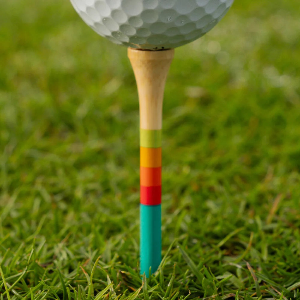 Close-up of a golf ball on a 3 1/4-inch bamboo tee, showing its teal, red, orange, and green gradient stripes.