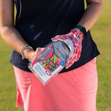 A woman opening a package of the neon mix pride performance golf tees. 