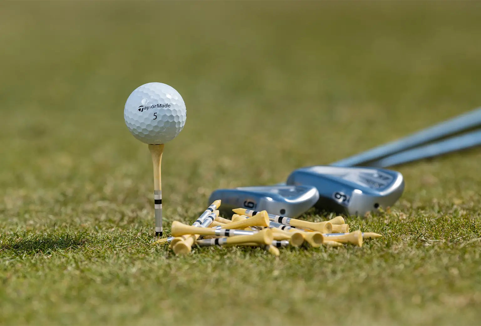 A taylormade golf ball positioned on top of a striped bamboo tee. 