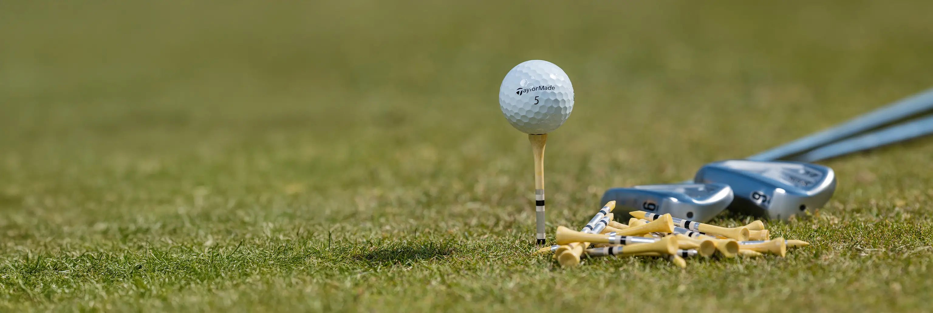 A taylormade golf ball positioned on top of a striped bamboo tee. 