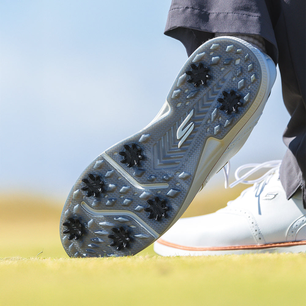 The bottom side of a persons right golf shoe showing the black widow spikes attached. 