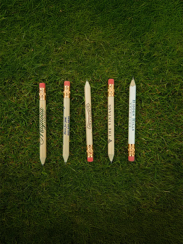 Five custom imprinted golf pencils positioned on green turf. 