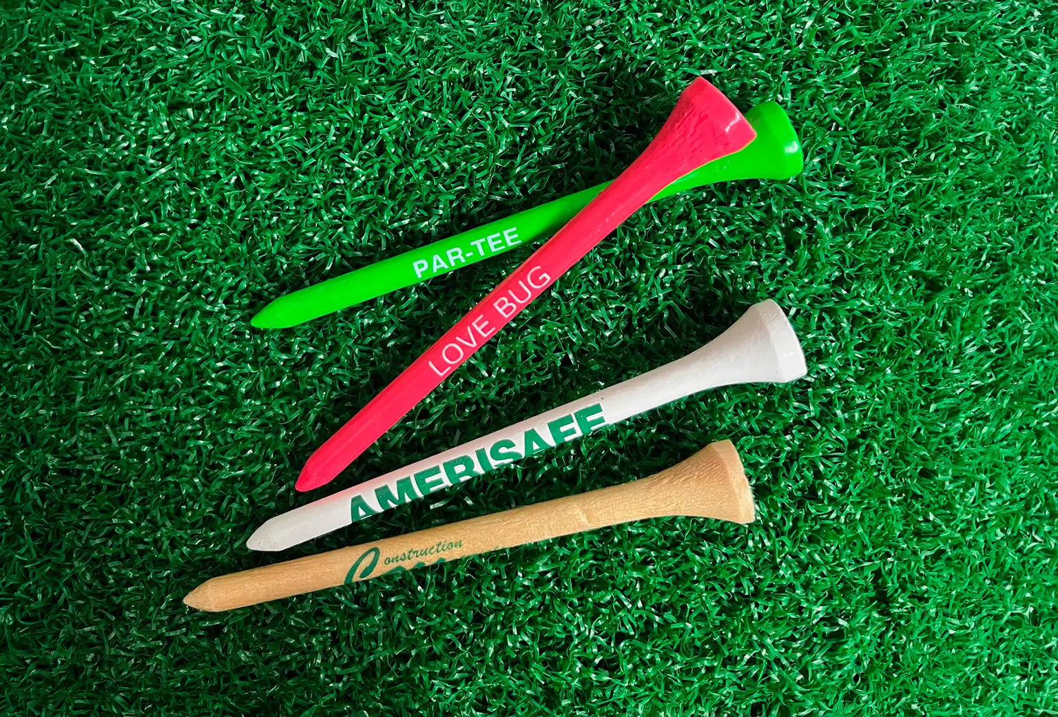 Four multi-colored wood golf tees positioned on green turf. 