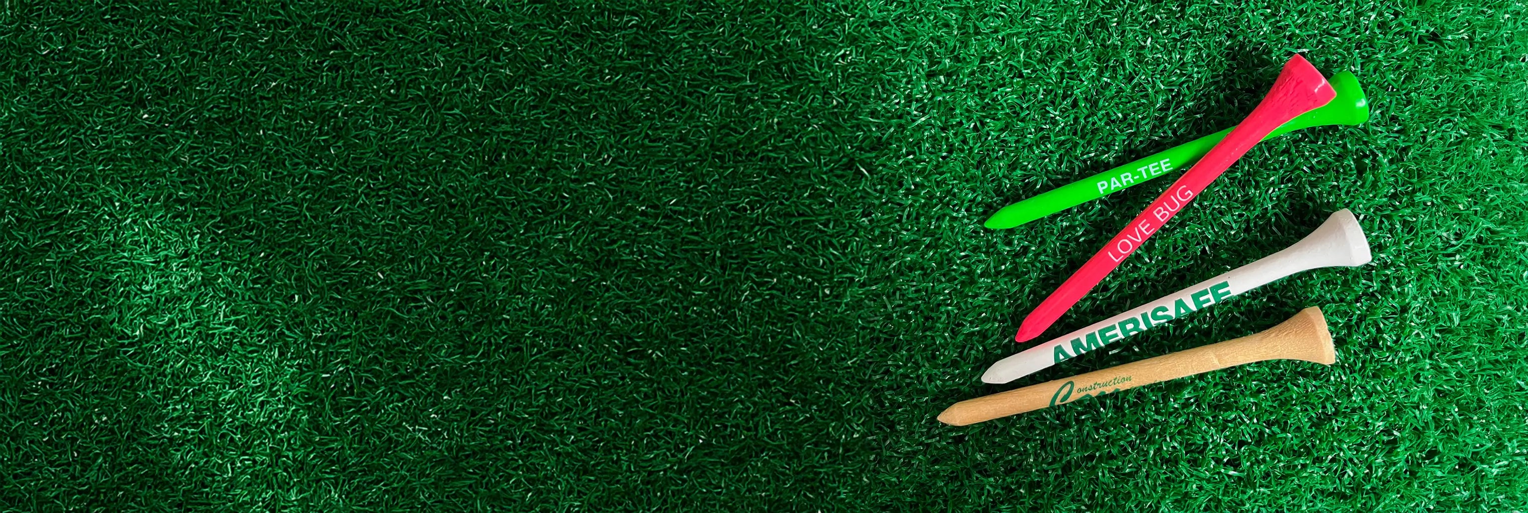 Four multi-colored wood golf tees positioned on green turf. 