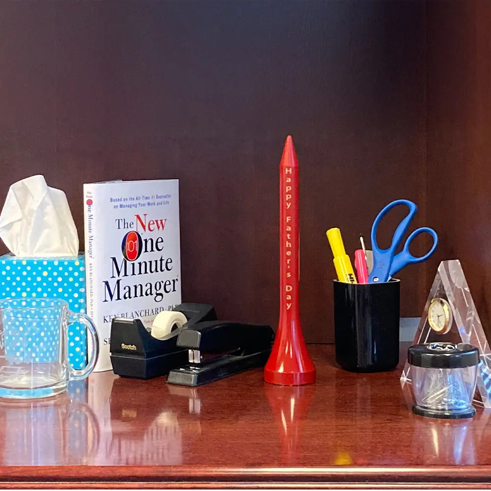 A red jumbo tee trophy on a desk. 