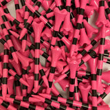 Close-up of pink and black golf tees scattered on a white background