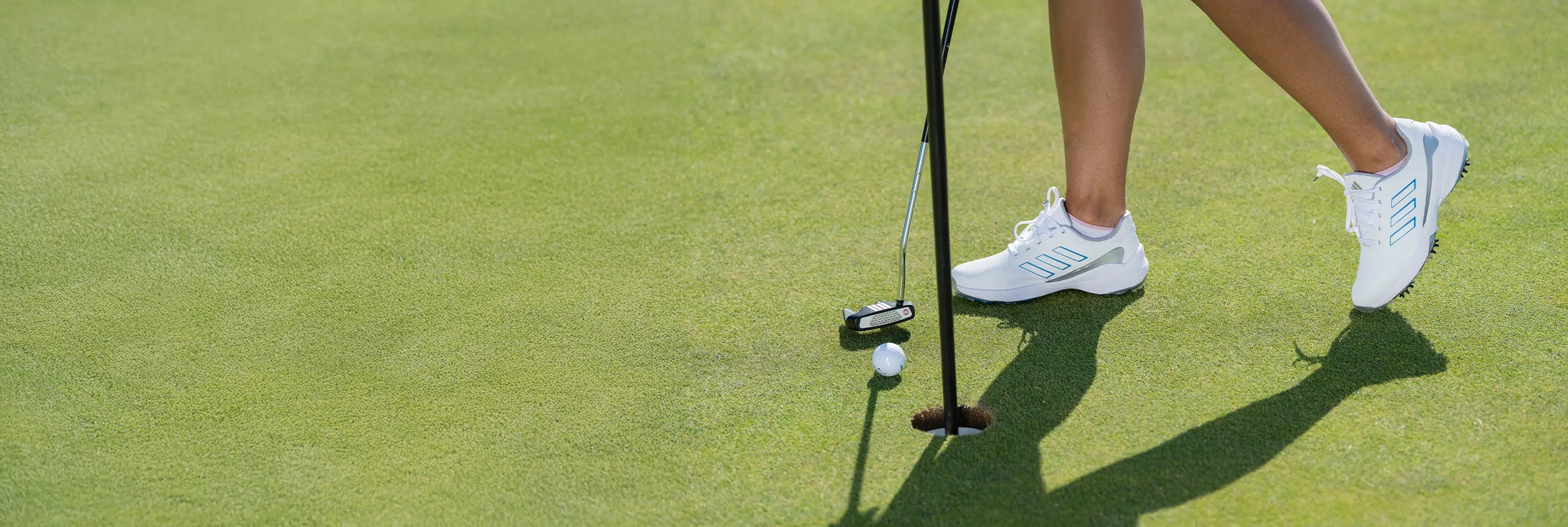 A woman putting a golf ball into a hole on a golf course. 