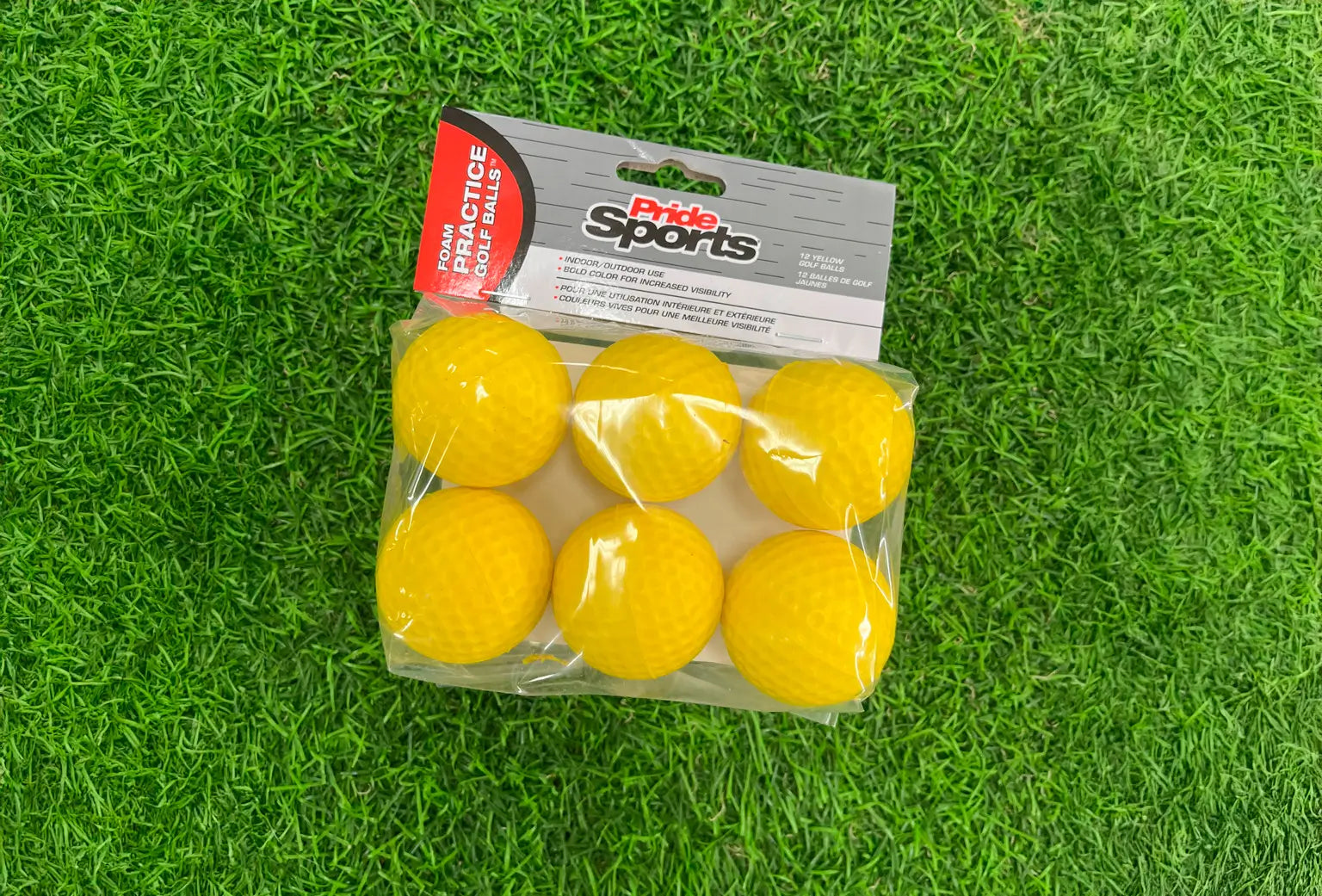 Practice yellow foam ball packaging positioned on a green turf. 