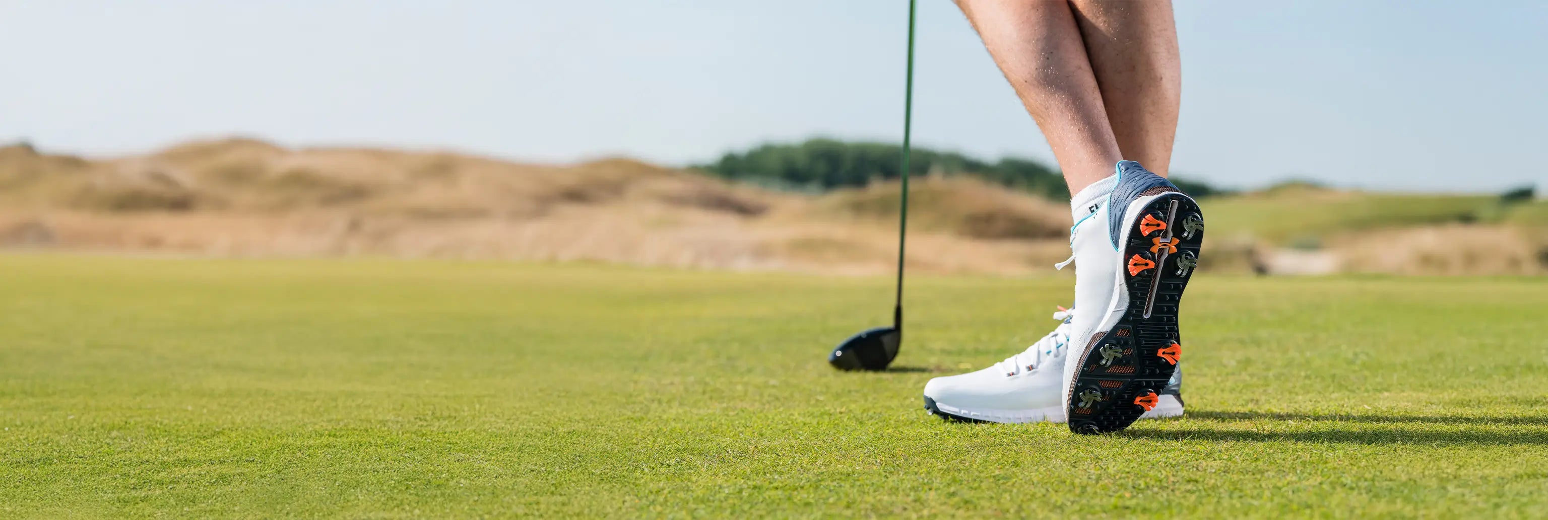 A man showing his golf spikes underneath the bottom of his golf shoes. 