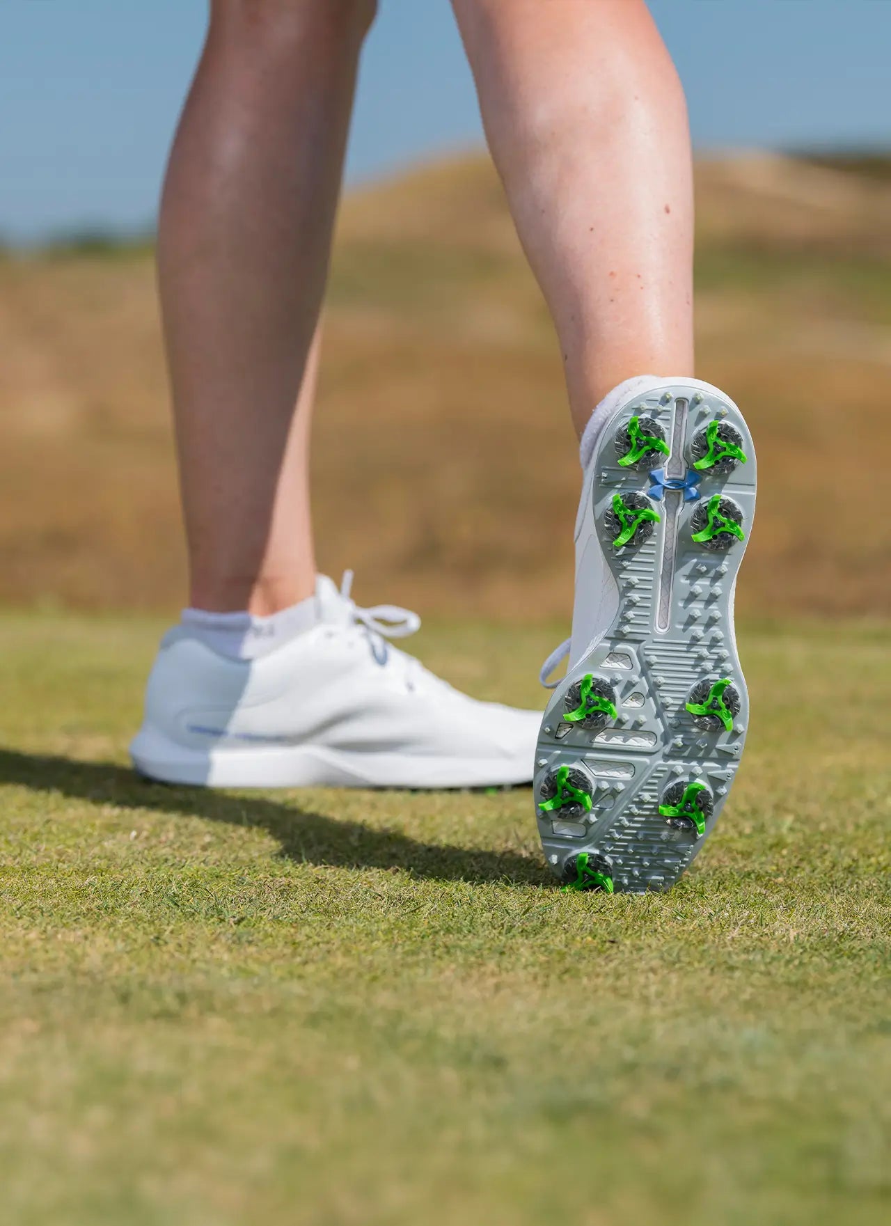 The bottom of a womans under armour shoes showing the tour flex pro golf spikes. 