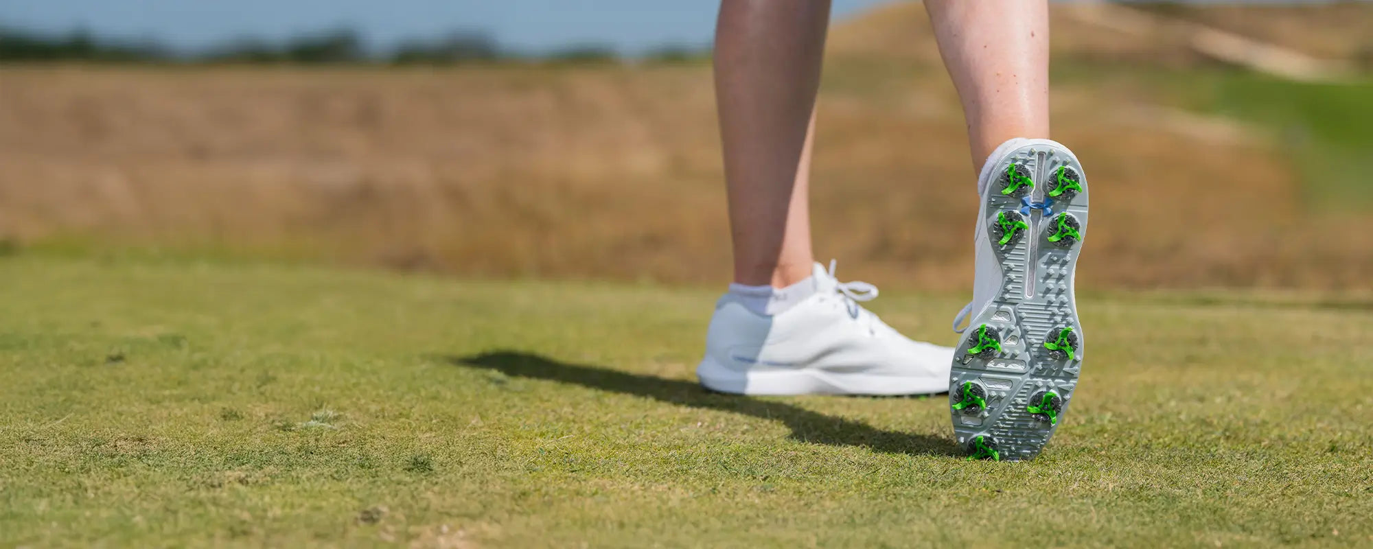 The bottom of a womans under armour shoes showing the tour flex pro golf spikes. 