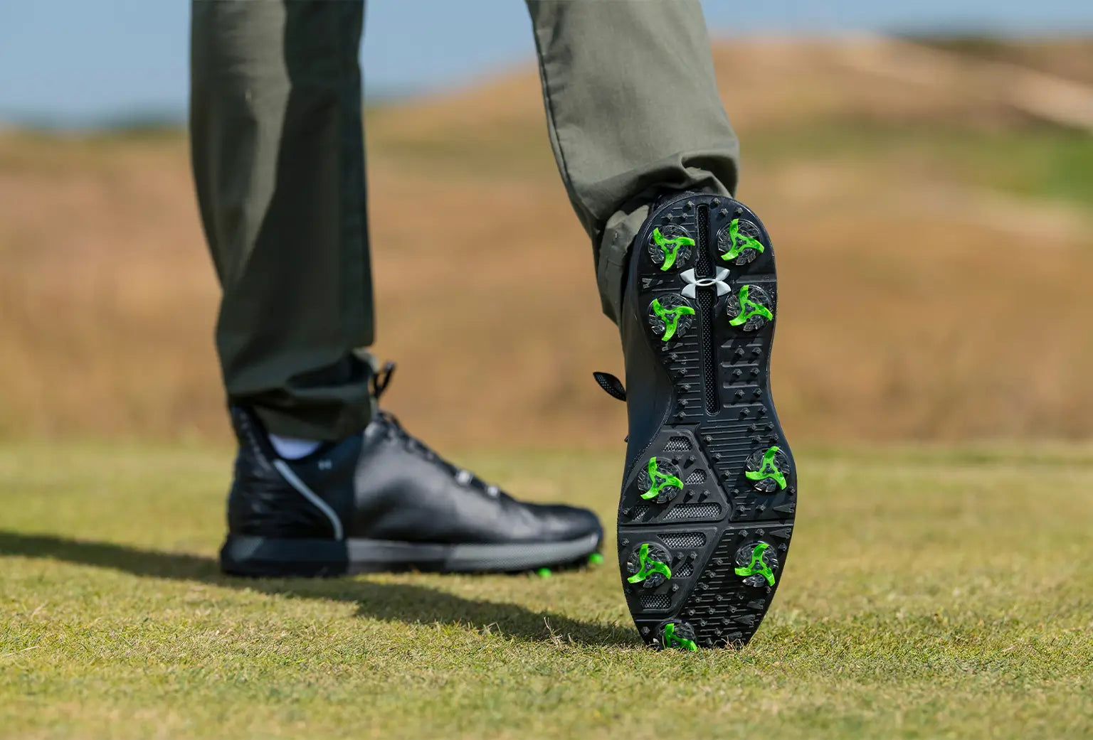 A person showing the underside of his golf shoe revealing the flex pro tour golf spikes attached to the shoe. 