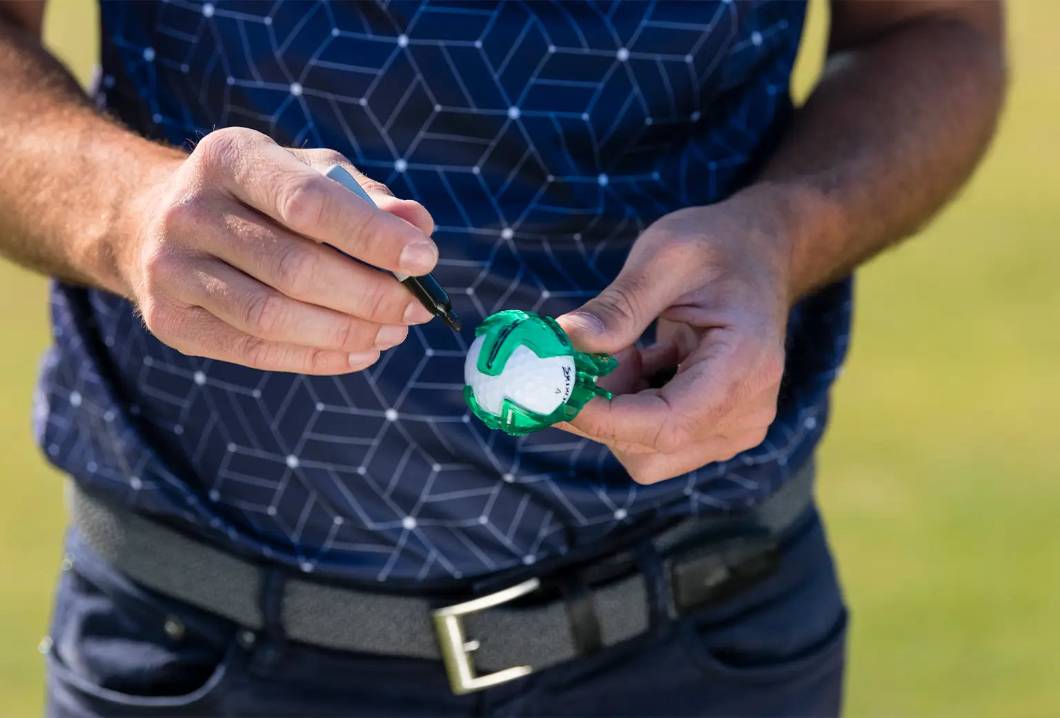 A man using a sharpie to mark his golf ball with the golf ball alignment tool.