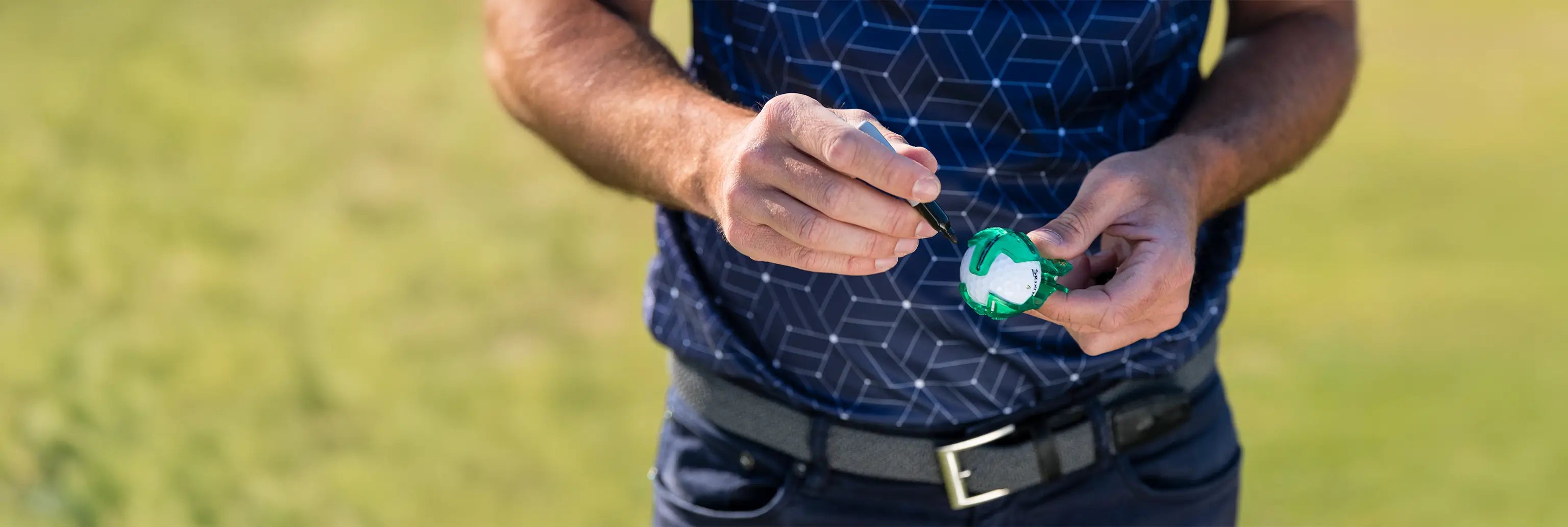 A man using a sharpie to mark his golf ball with the golf ball alignment tool.