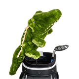 A green plush crocodile peeks from a golf bag, alongside a golf club.