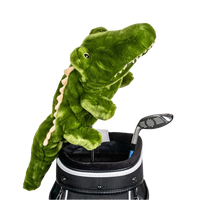 A green plush crocodile peeks from a golf bag, alongside a golf club.