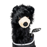 A black bear-shaped golf club head cover sitting in a golf bag, with a club peeking out.