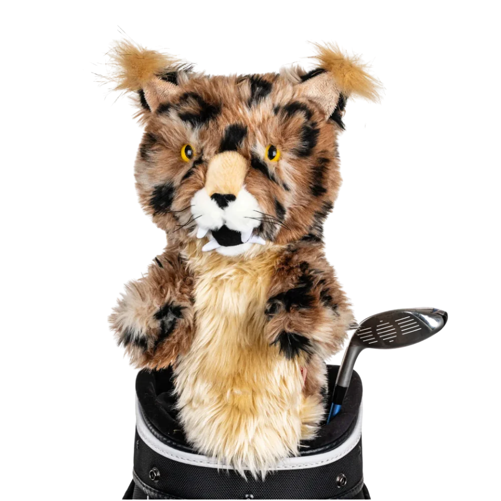 A bobcat-shaped golf club head cover sitting in a golf bag, with a club peeking out.