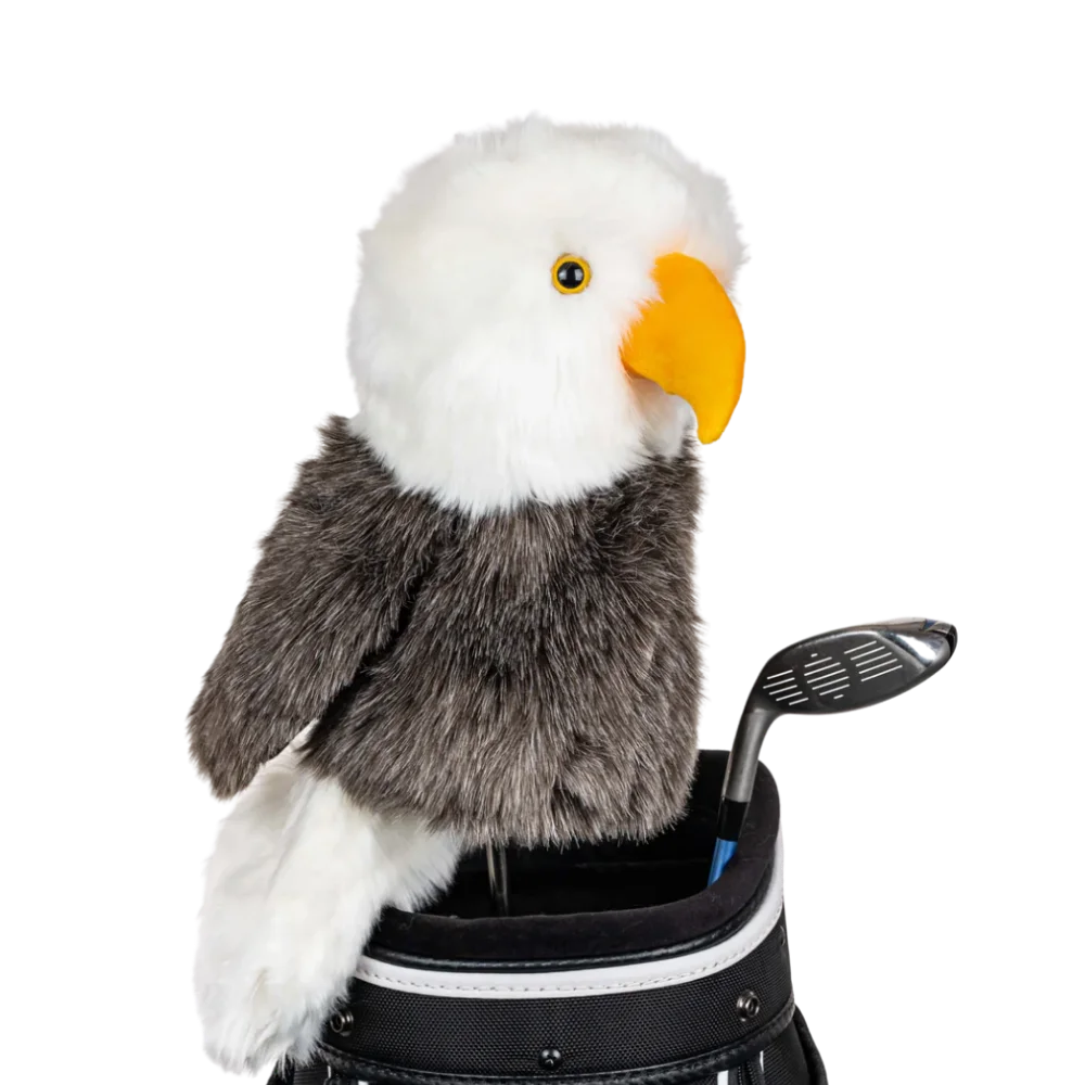 An eagle-shaped golf club head cover sitting in a golf bag, with a club peeking out.