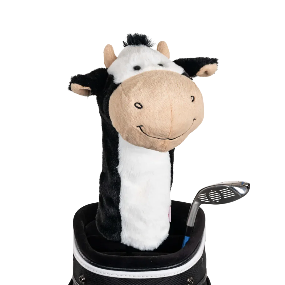 A cow-shaped golf club head cover sitting in a golf bag, with a club peeking out.