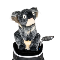 A koala-shaped golf club head cover sitting in a golf bag, with a club peeking out.