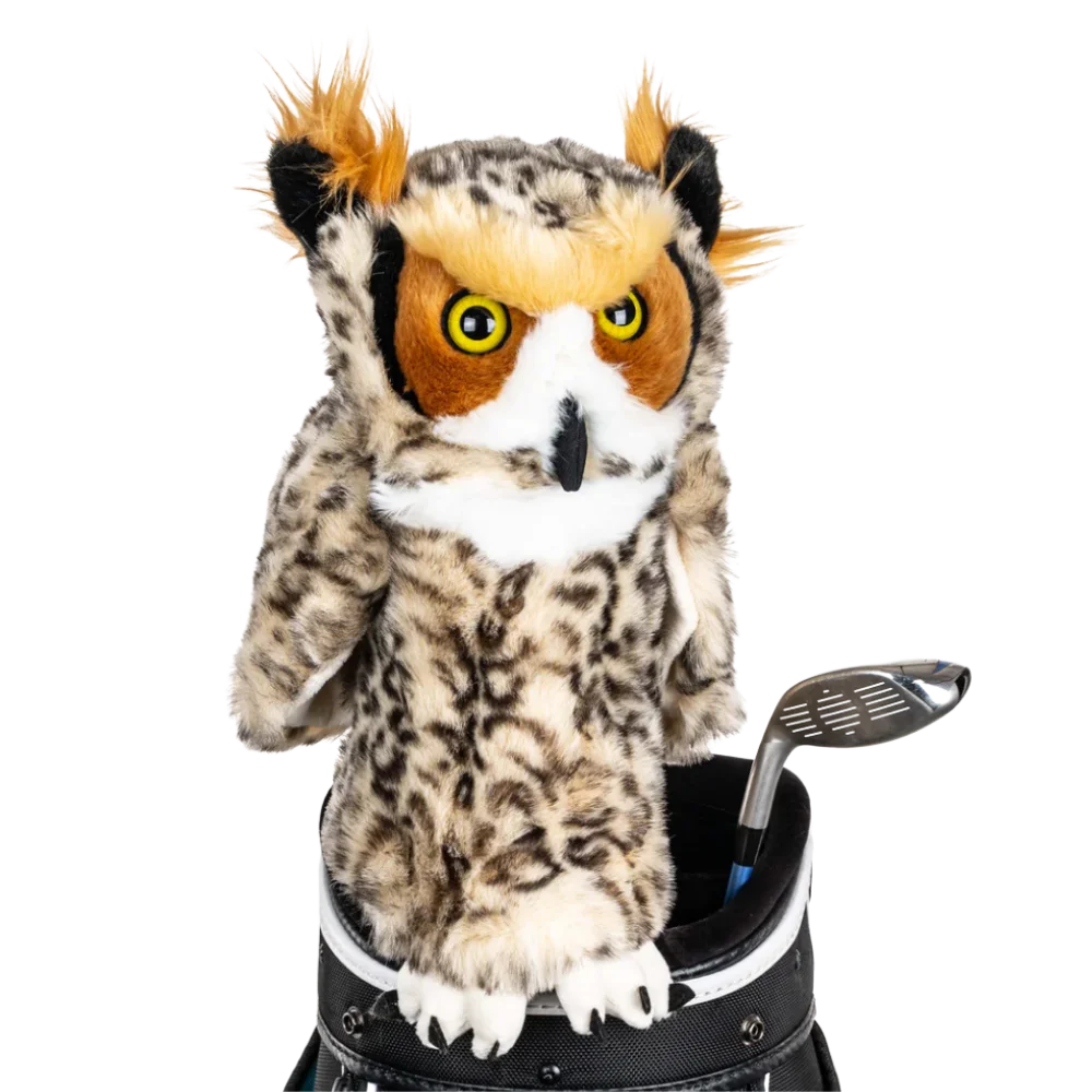 An owl-shaped golf club head cover sitting in a golf bag, with a club peeking out.
