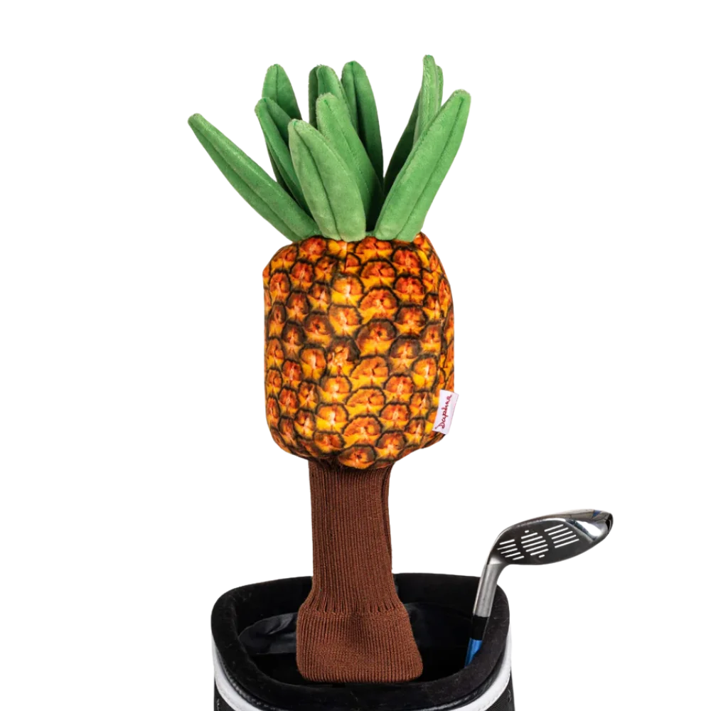 A pineapple-shaped golf club head cover sitting in a golf bag, with a club peeking out.