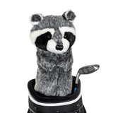 A raccoon-shaped golf club head cover sitting in a golf bag, with a club peeking out.