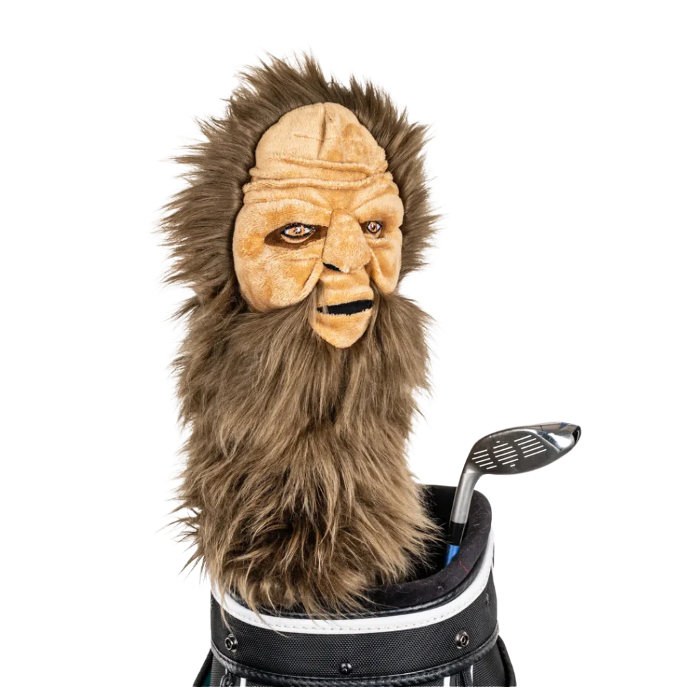 A Sasquatch-shaped golf club head cover sitting in a golf bag, with a club peeking out.