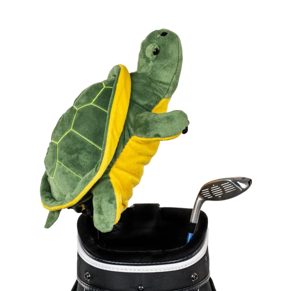 A turtle-shaped golf club head cover sitting in a golf bag, with a club peeking out.