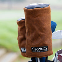 Honors Collection brown canvas barrel driver headcovers resting on clubs in a golf bag on the course.