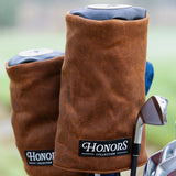 Honors Collection brown canvas barrel fairway headcovers resting on clubs in a golf bag on the course.