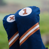 Close-up of Honors Collection navy canvas driver and fairway headcovers with brown and white diagonal stripes on the course.