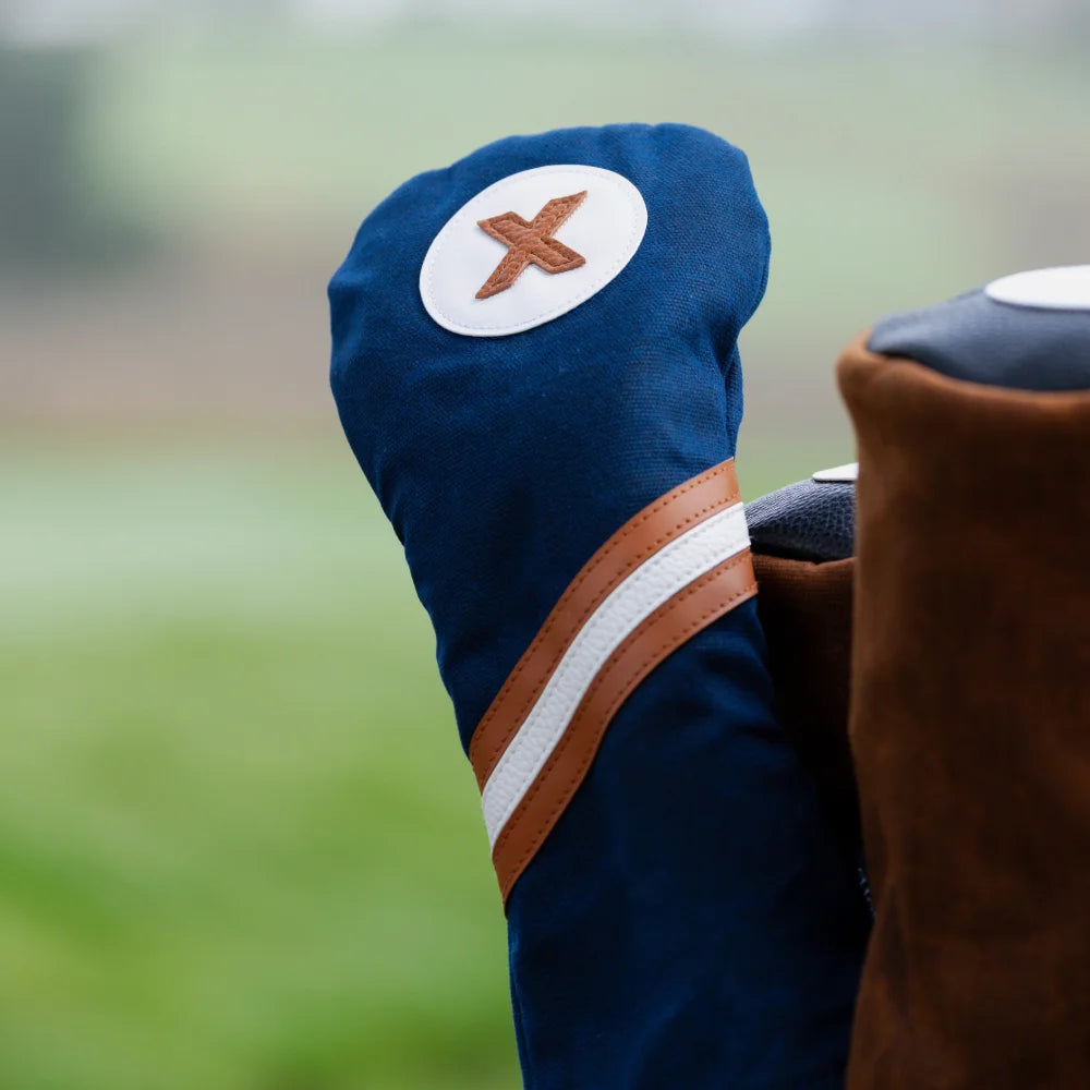 Close-up of the Honors Collection navy canvas fairway headcover with brown and white diagonal stripe and X patch on a golf bag.