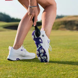 A close-up of a person's foot wearing a white golf shoe with purple accents, holding a Prosoft brush on a grass golf course.