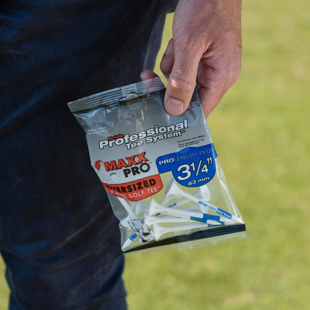 Hand holding a package of golf tees with grass in the background