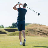 A golfer is swinging a club on a sunny golf course and wearing scorpion stinger golf spikes.