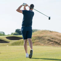 A golfer is swinging a club on a sunny golf course and wearing scorpion stinger golf spikes.