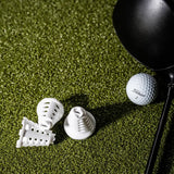 Collapsed white simulator golf tees compressing next to a golf ball and driver.